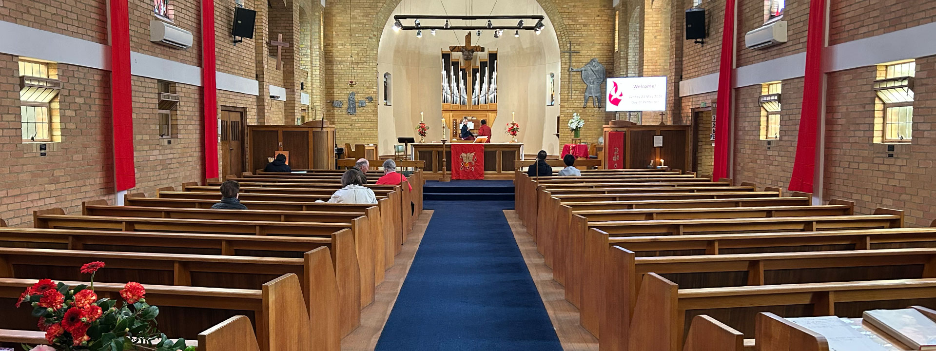 Inside the church with pews either side of the middle aisle and an organ behind the alter at the front